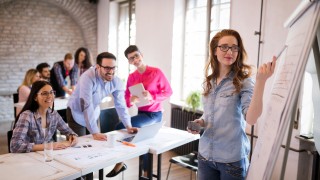 Portrait of young attractive architect doing presentation to her coworkers