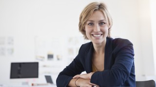 Portrait of smiling young woman at her desk in a creative office