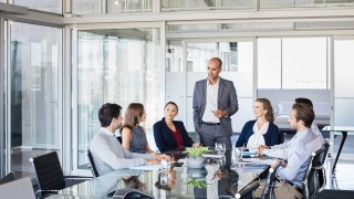 Human resource manager training people about company and future prospects. Group of businesspeople sitting in meeting room and listening to the speaker. Leader man training his work group in a conference room.