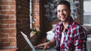 Cheerful man using computer at home. Concept free people working at home. Freelancer.